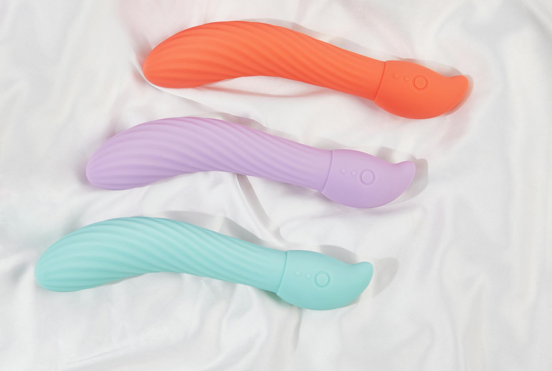 Una mano che tiene un vibratore arancione su sfondo viola, simbolo di sensualità moderna consapevole