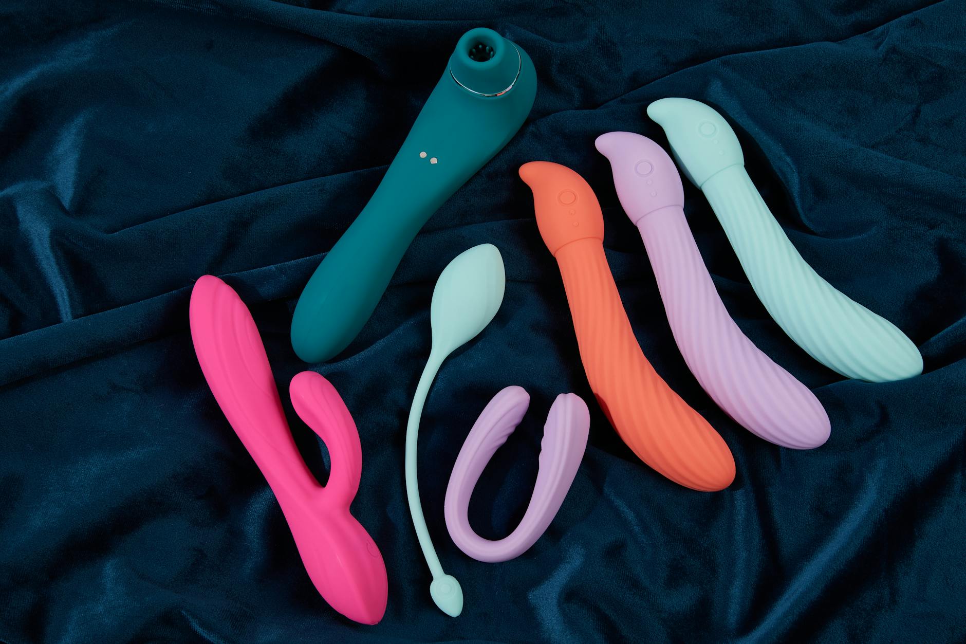 Vibratori colorati in silicone disposti su tessuto blu scuro