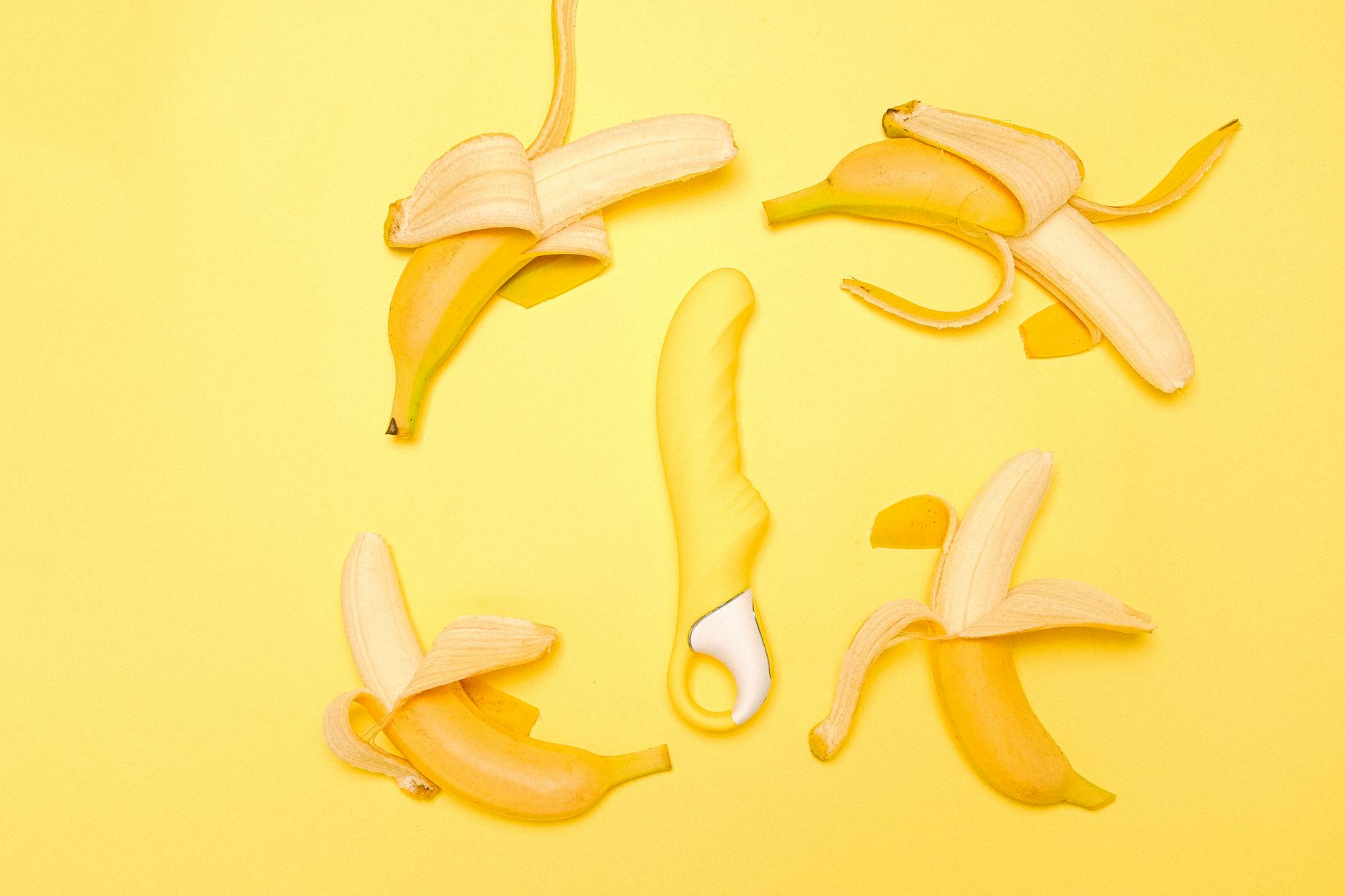 Vibratore al limone giallo su sfondo giallo con banane sbucciate