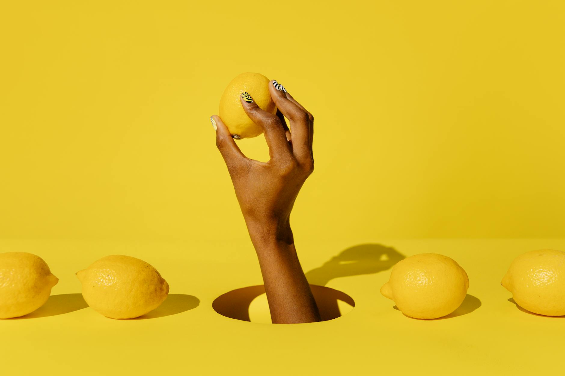 Mano che tiene un limone su sfondo giallo vivace, che trasmette freschezza e energia sensuale