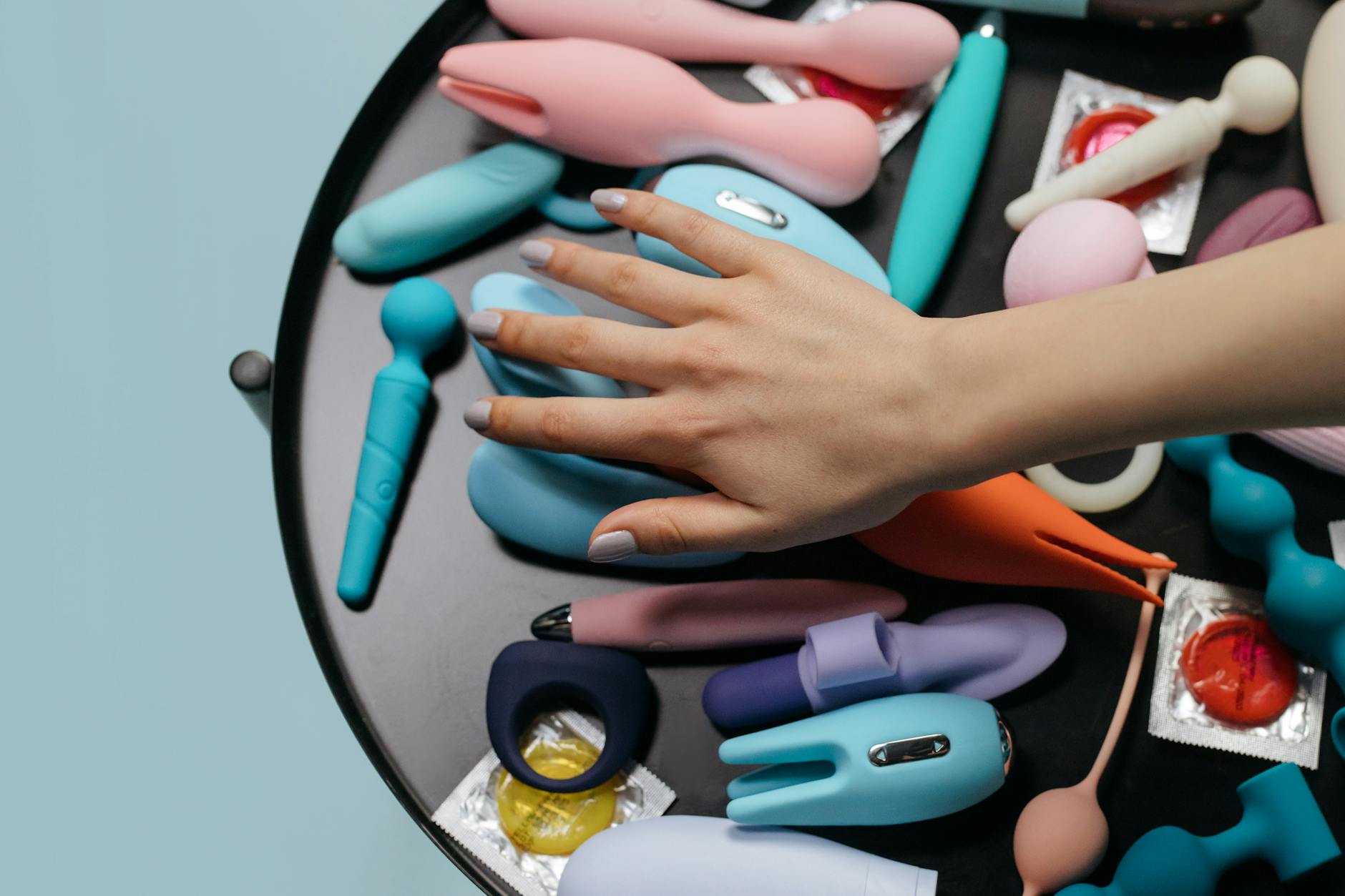 Un vibratore clitorideo in silicone blu tenuto in mano su sfondo viola, simbolo di auto-amore e sessualità consapevole