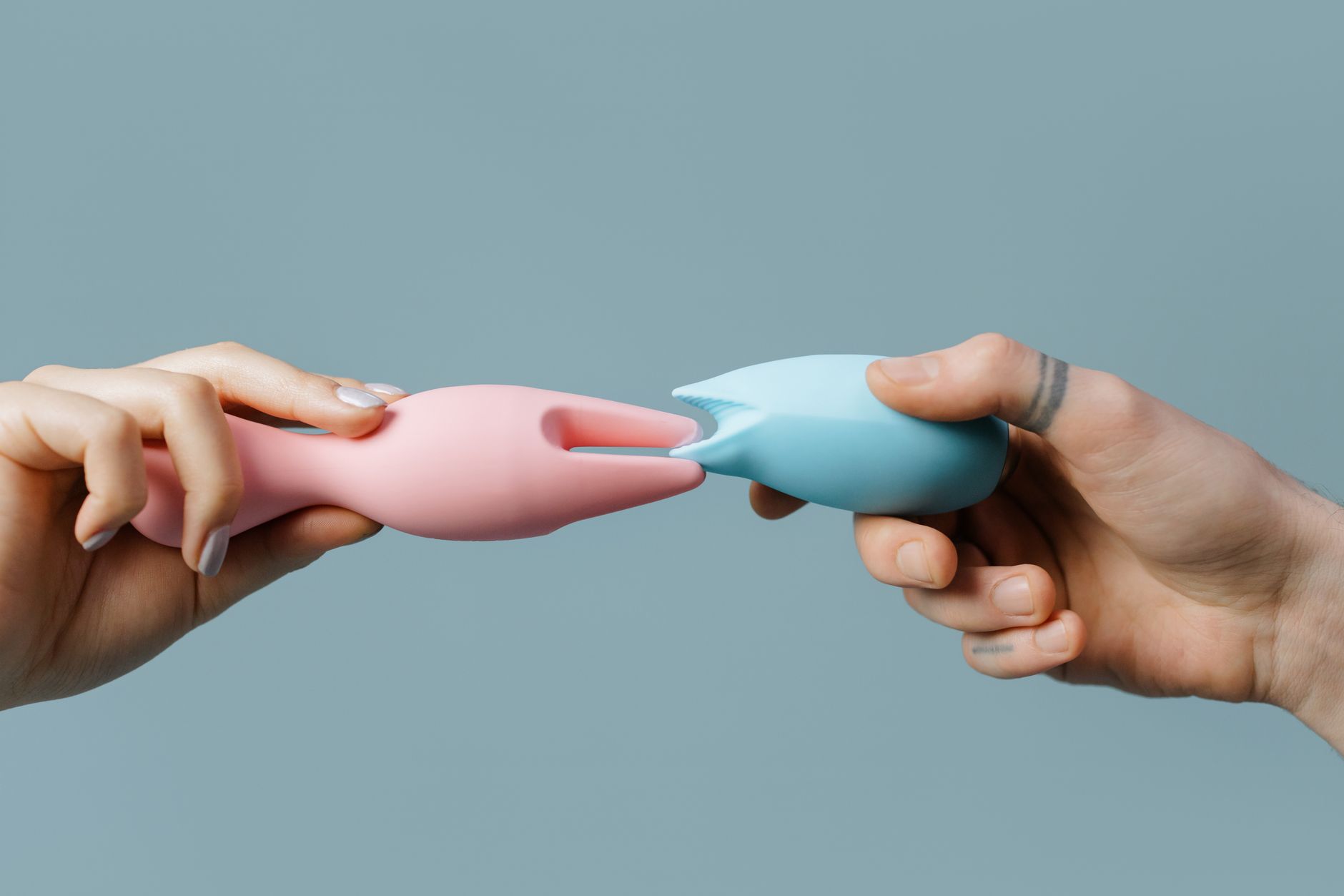 Mani che tengono giocattoli in silicone colorati, simbolo di piacere e intimità