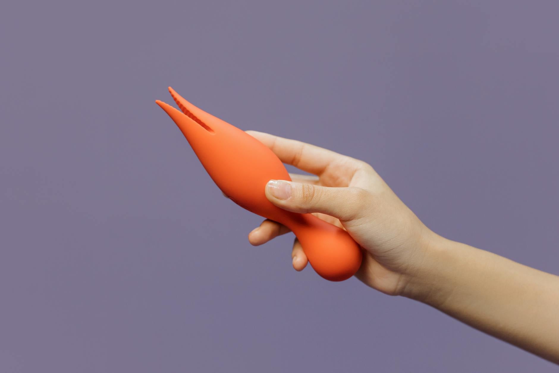 Una mano tiene il vibratore al limone su uno sfondo viola minimalista che mostra la sensualità moderna